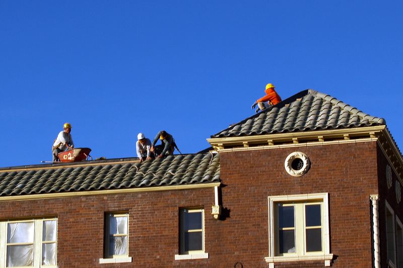 Roofers on the roof of a brick building